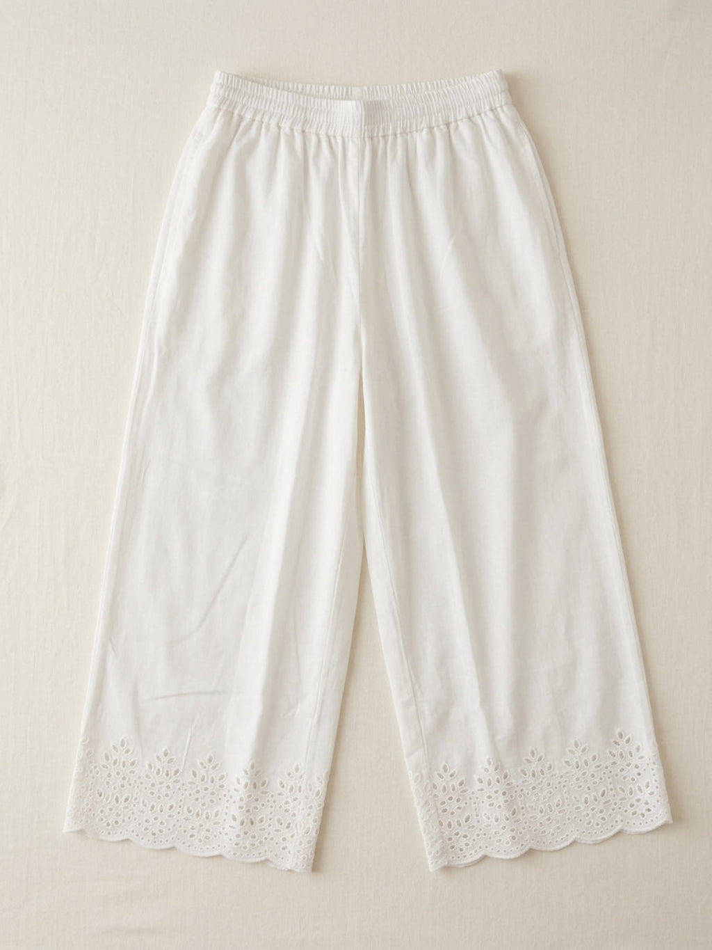 White cotton palazzo pants with scalloped floral embroidered hem, flat lay