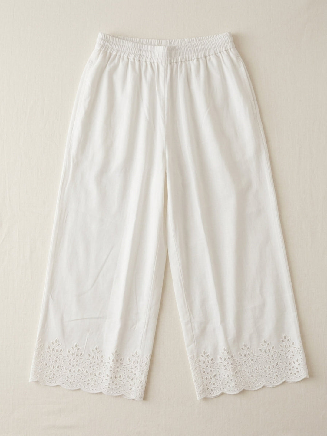 White cotton palazzo pants with scalloped floral embroidered hem, flat lay